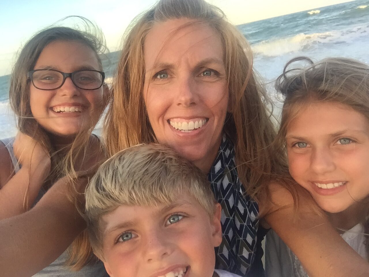 A woman and her children are taking a selfie on the beach, showcasing their empowered post-split support.