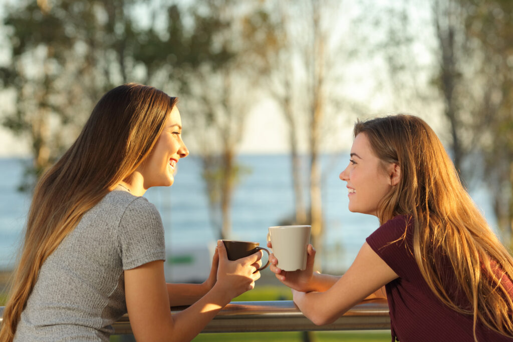 Two young women enjoying services on a balcony overlooking the ocean.