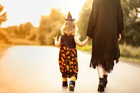 A co-parent and child walking down a road in a Halloween costume, upholding Halloween traditions.
