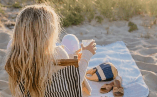 A woman sits on a striped beach chair on sand, holding a cup, with a hat and bag beside her. Overlaid text reads: “Documenting Abuse” – sharing my experiences documenting abuse on the Divorce Diaries Podcast.